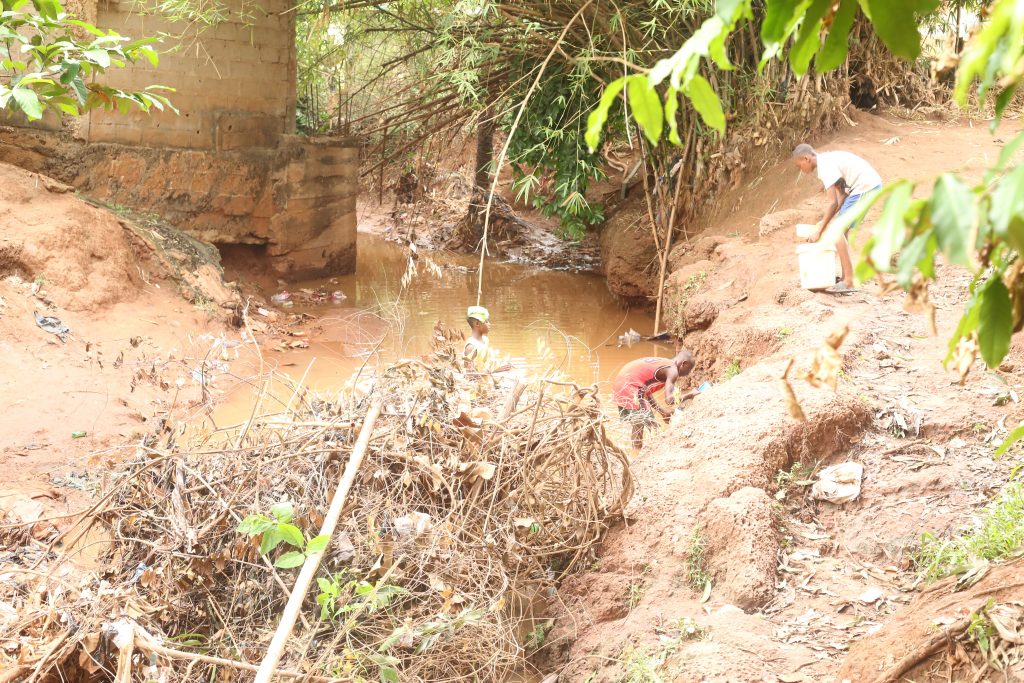 People fetch water from the dirty shallow stream in Okilo 