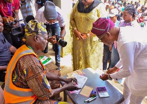 An elderly OSIEC ad hoc staff member without a nose mask attending to Governor Oyetola during voting in Osun state